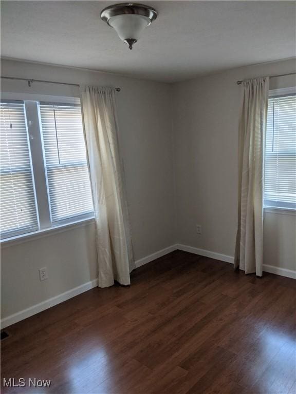 spare room with dark wood finished floors and baseboards