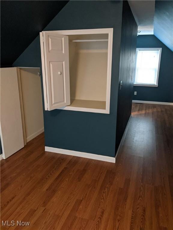 bonus room with dark wood-type flooring, lofted ceiling, and baseboards