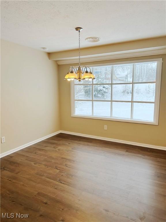 unfurnished dining area with a wealth of natural light, baseboards, a chandelier, and dark wood-type flooring