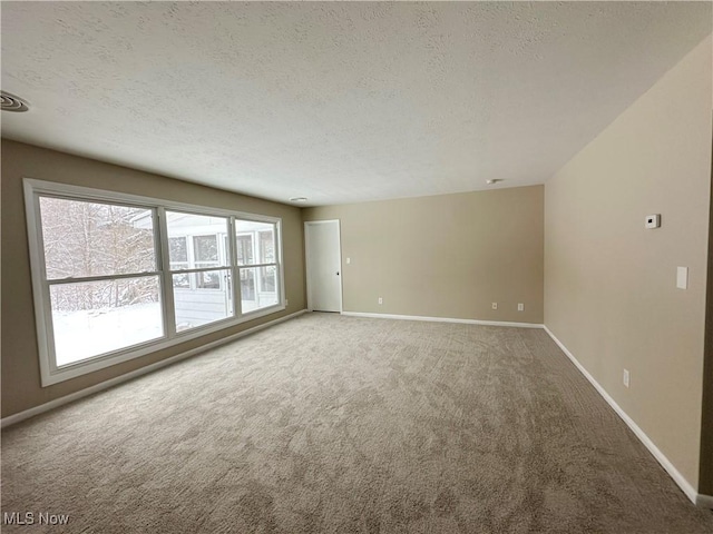 carpeted spare room featuring baseboards and a textured ceiling