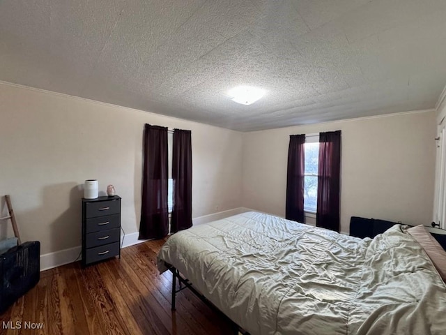 bedroom with a textured ceiling, crown molding, dark wood finished floors, and baseboards