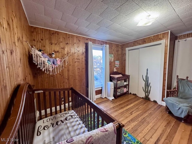 bedroom with a closet, wooden walls, and wood finished floors