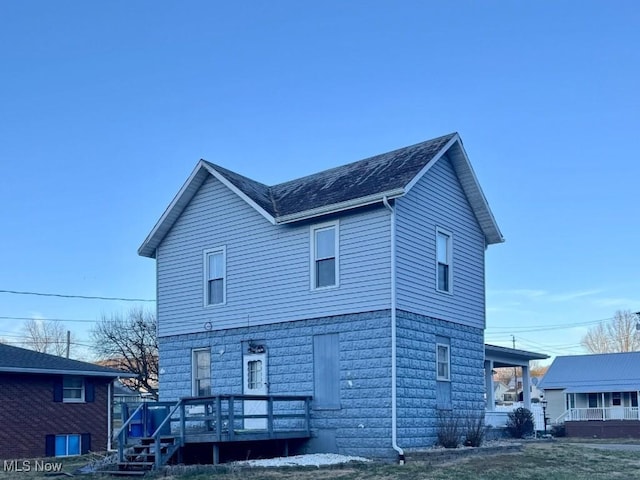 rear view of property with a shingled roof and a porch