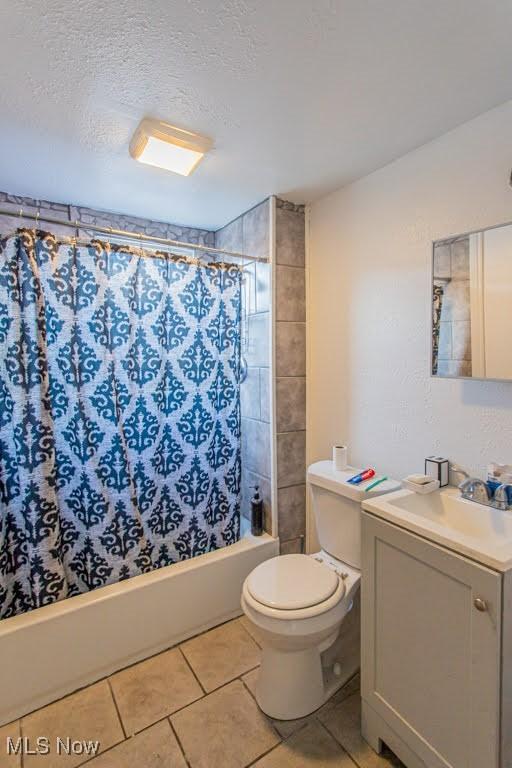 bathroom with toilet, shower / tub combo with curtain, tile patterned flooring, a textured ceiling, and vanity