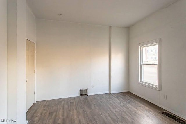 unfurnished room featuring visible vents, baseboards, and wood finished floors