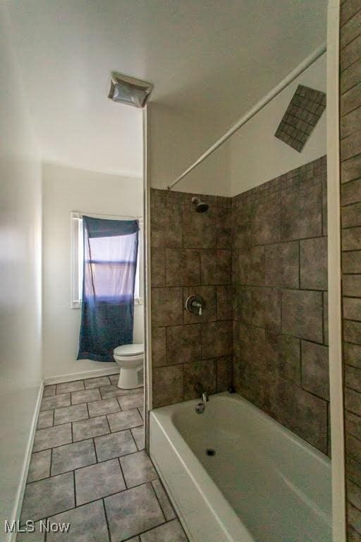 bathroom with toilet, shower / bath combination, and baseboards