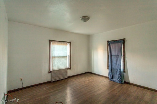 unfurnished room with baseboards and wood finished floors