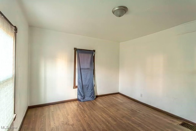 empty room featuring visible vents, baseboards, and wood finished floors