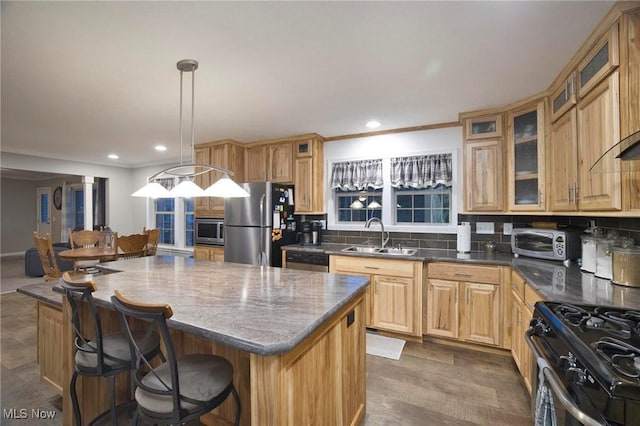 kitchen with a toaster, decorative backsplash, a kitchen island, stainless steel appliances, and a sink