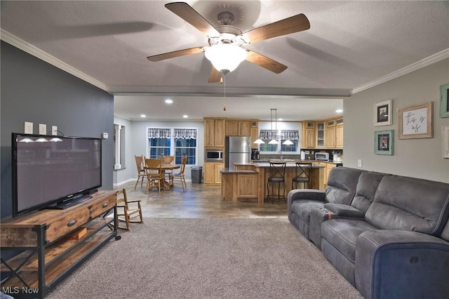 living area featuring a textured ceiling, ceiling fan, recessed lighting, wood finished floors, and ornamental molding