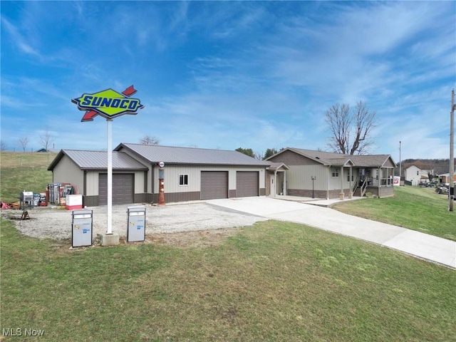 view of front of property featuring metal roof, a front lawn, and driveway