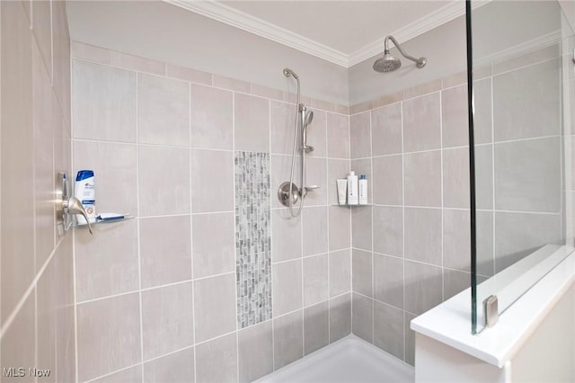 bathroom with ornamental molding and a tile shower