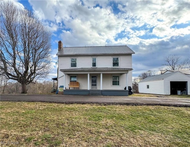 view of front of house with covered porch, a chimney, metal roof, and a front yard