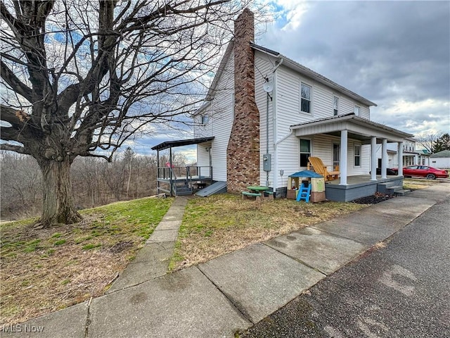 view of home's exterior featuring covered porch and a chimney