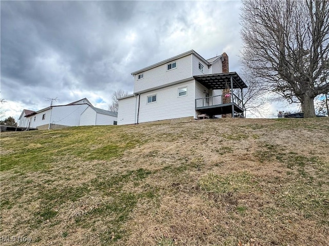 rear view of property featuring a yard and a chimney