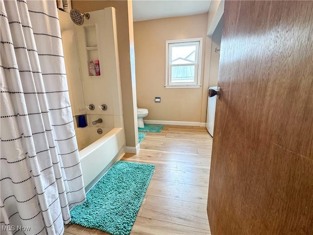 full bath featuring shower / bath combination with curtain, wood finished floors, toilet, and baseboards