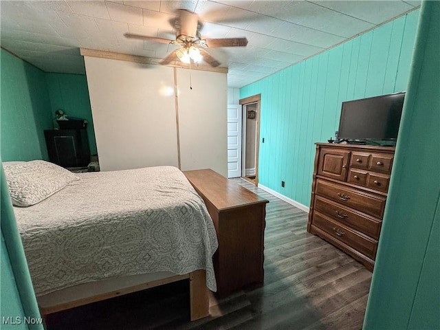 bedroom featuring a ceiling fan, baseboards, and dark wood-type flooring