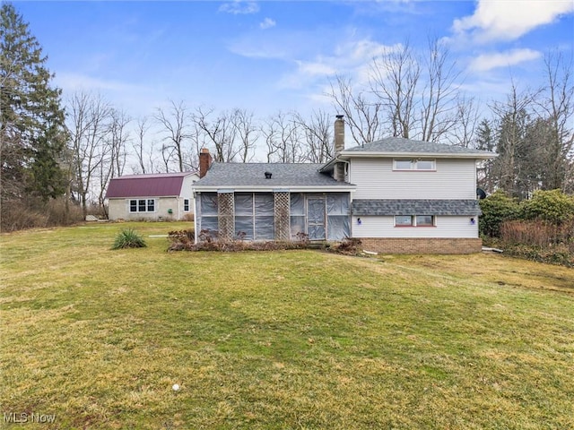 back of property featuring a sunroom, a chimney, roof with shingles, a yard, and brick siding