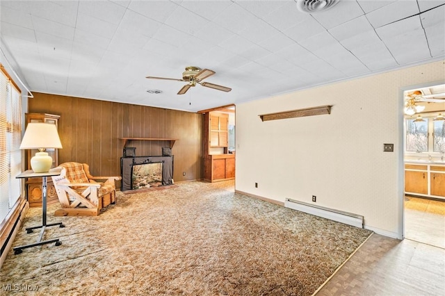 living room featuring ceiling fan, a baseboard radiator, wood walls, a fireplace with flush hearth, and visible vents