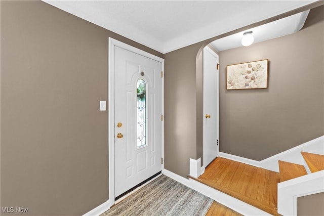 foyer with baseboards, arched walkways, and wood finished floors