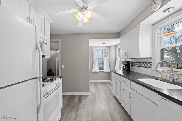 kitchen featuring white appliances, a sink, a healthy amount of sunlight, decorative backsplash, and dark countertops