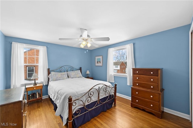 bedroom with ceiling fan, wood finished floors, and baseboards