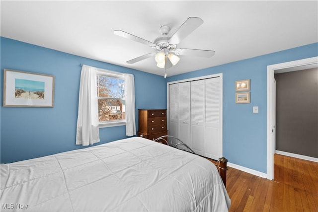 bedroom with hardwood / wood-style floors, ceiling fan, baseboards, and a closet