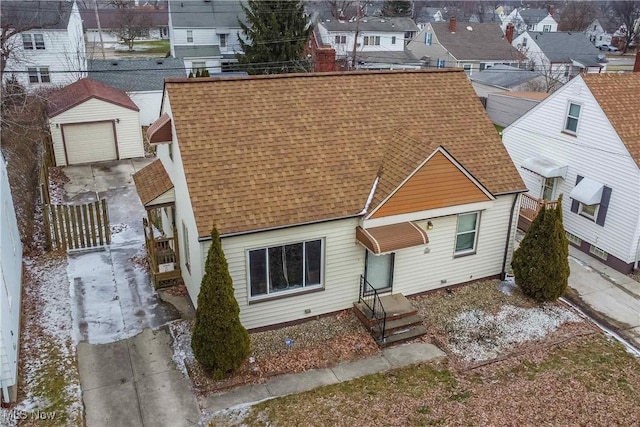 back of property featuring a garage, driveway, a residential view, and roof with shingles