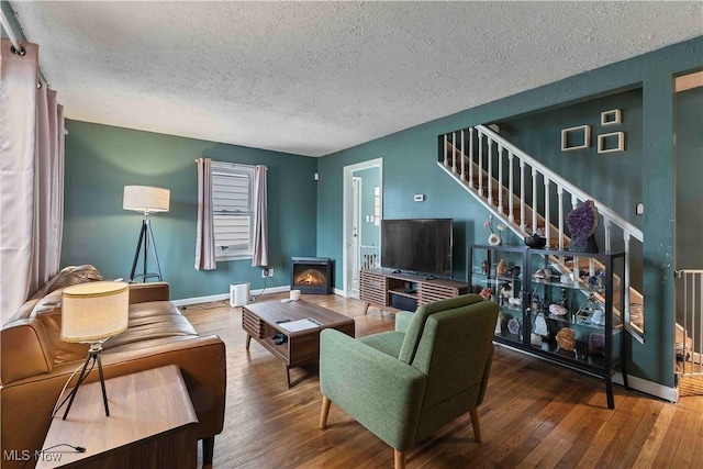 living area with hardwood / wood-style flooring, stairs, baseboards, and a textured ceiling