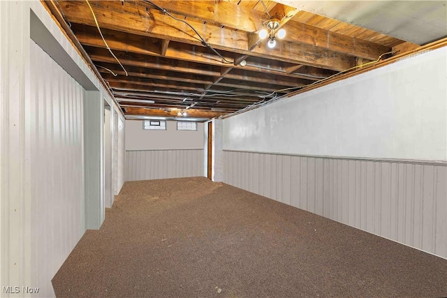 below grade area featuring carpet flooring and wainscoting