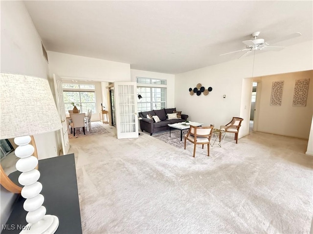 living room with a ceiling fan, french doors, light carpet, and vaulted ceiling