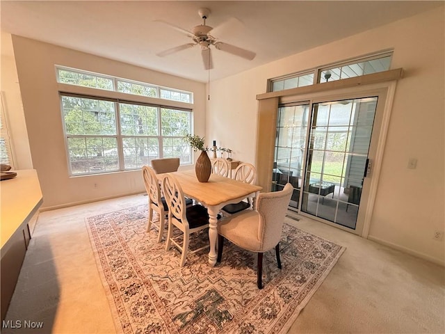 dining space with light carpet, ceiling fan, and baseboards