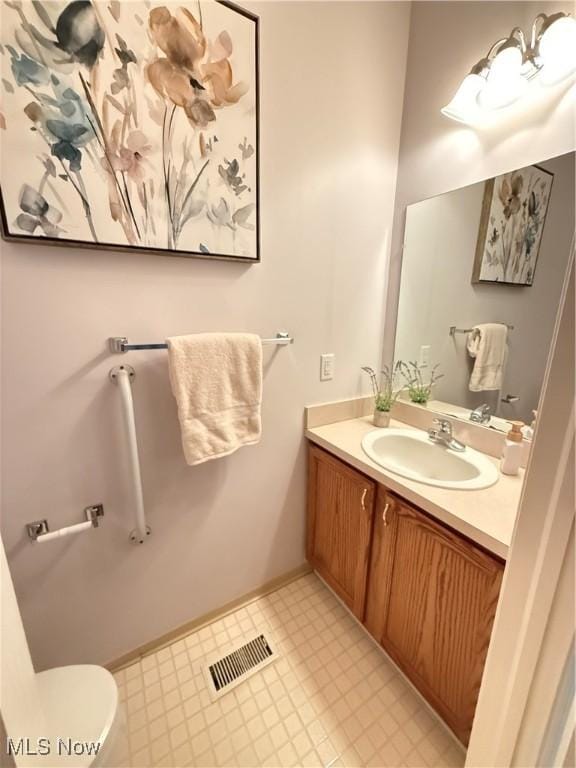 bathroom with toilet, vanity, baseboards, visible vents, and tile patterned floors