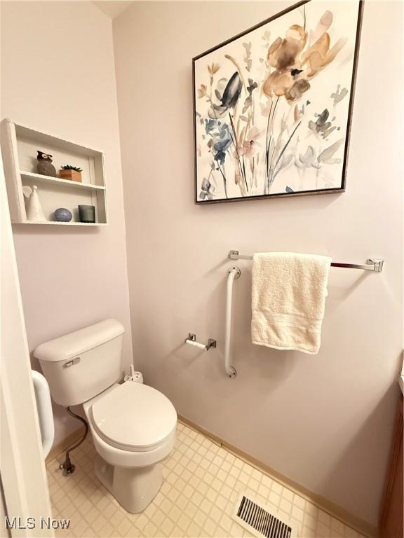 bathroom with baseboards, visible vents, toilet, and tile patterned floors