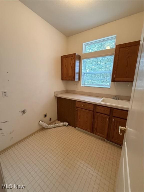 kitchen with light countertops, brown cabinetry, and a sink