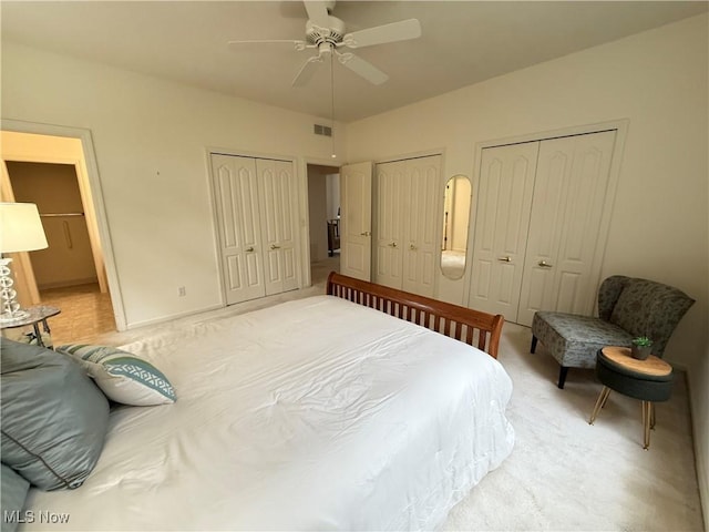 bedroom with a ceiling fan, visible vents, and two closets