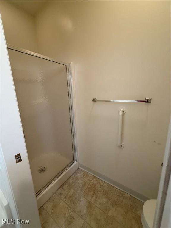 full bath with toilet, a shower stall, baseboards, and tile patterned floors