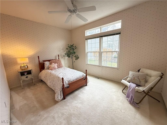 carpeted bedroom with a ceiling fan, visible vents, and wallpapered walls