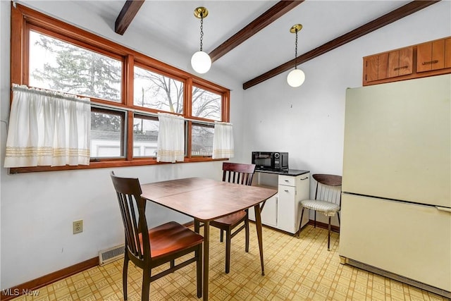 dining room featuring vaulted ceiling with beams, light floors, and baseboards