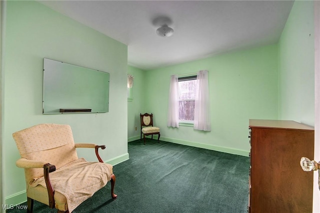 sitting room featuring dark colored carpet and baseboards