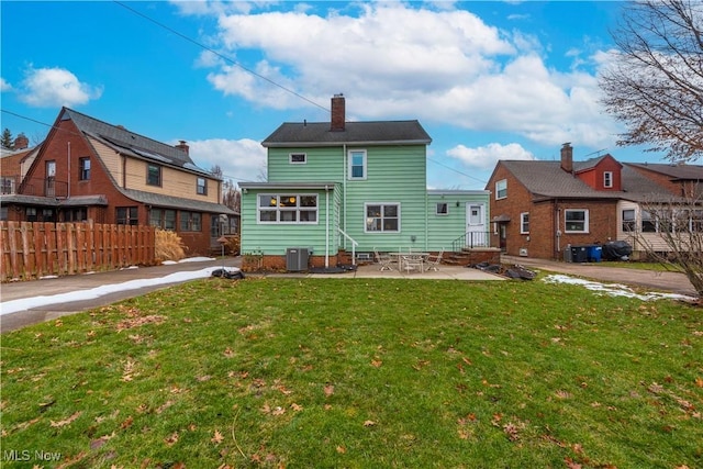 rear view of property with entry steps, a patio, fence, a yard, and central AC