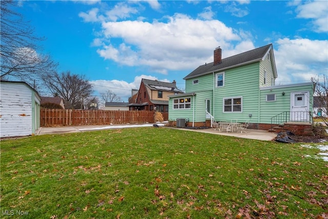 back of house featuring central AC, fence, a lawn, a chimney, and a patio area