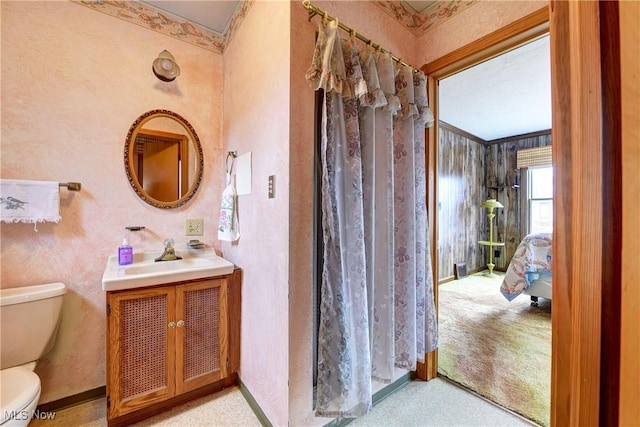 bathroom with toilet, baseboards, crown molding, and vanity