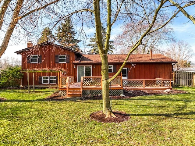 rear view of house featuring a chimney, fence, a deck, and a yard