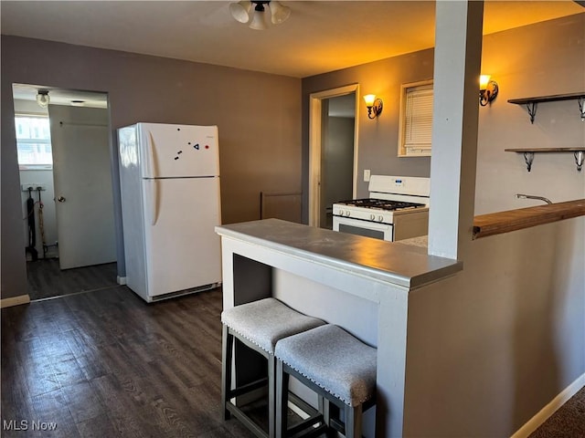 kitchen featuring white appliances, a breakfast bar, dark wood-style flooring, a peninsula, and open shelves