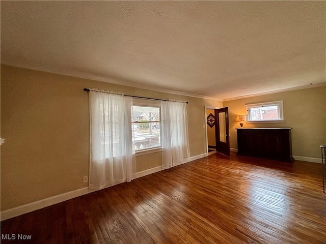 unfurnished living room featuring ornamental molding, plenty of natural light, hardwood / wood-style flooring, and baseboards