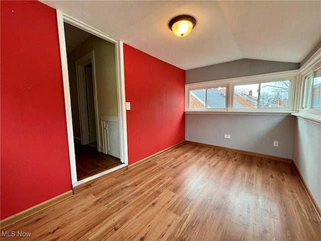 unfurnished room featuring lofted ceiling, wood finished floors, and baseboards