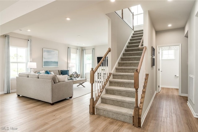 staircase with baseboards, wood finished floors, a wealth of natural light, and recessed lighting