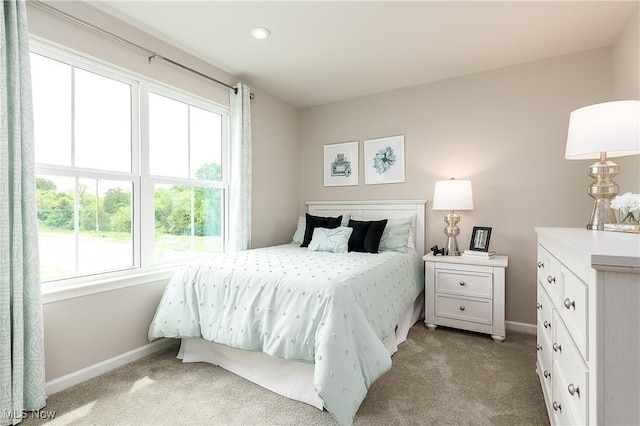 bedroom with light carpet, multiple windows, and baseboards