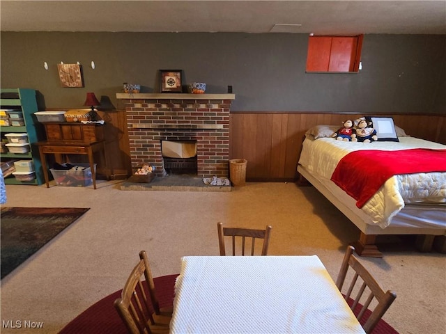 bedroom featuring carpet floors, a brick fireplace, a wainscoted wall, and wood walls